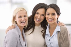 Portrait of three female coworkers standing together with smiles